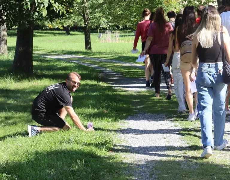 Fabio Meazza crouching by a grassy path during an outdoor group activity